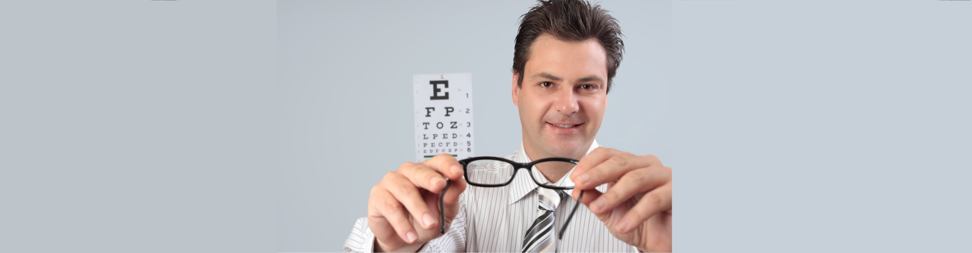 an optometrist putting eyeglasses spectacles on a customer patient